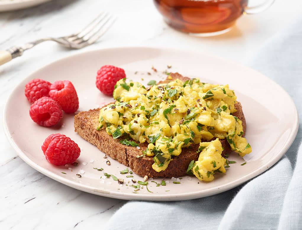 Huevos revueltos suaves con hierbas sobre pan tostado